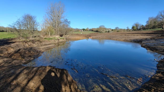 Image of a large pond - part of the recently completed Kyd Brook wetlands project. The pond is surrounded by bare soil but this will soon be colonised by marginal plants which will form part of the wetland ecosphere